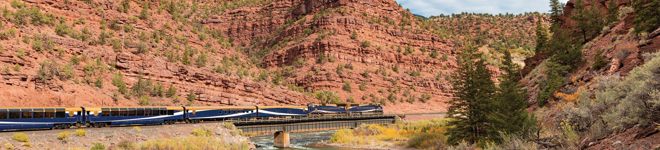 Rocky Mountaineer train travelling over a river in Red Canyon, Utah